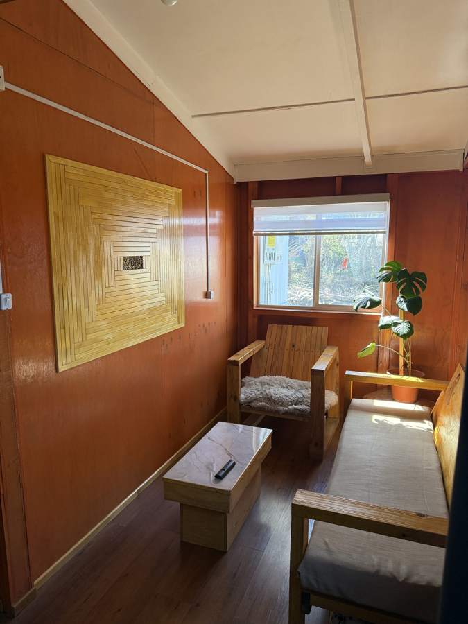 Living compartido con sillón y sofá de madera